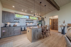 A modern kitchen with wooden cabinets, a central island, and pendant lighting. - Mountain Views, Hot Tub & Game Room w/ Skee-Ball (Gatlinburg)