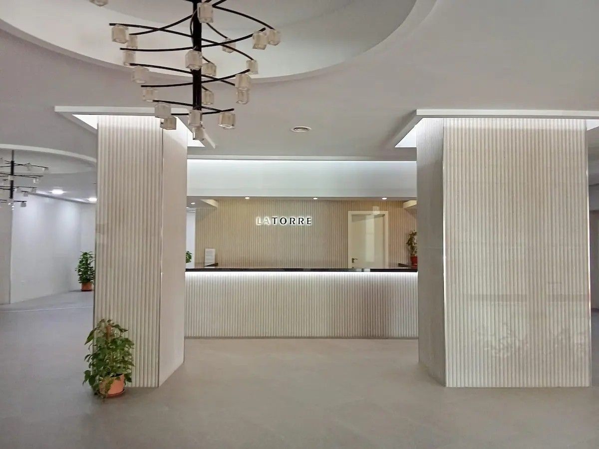 A modern reception area with a central desk, vertical columns, and a ceiling light fixture.