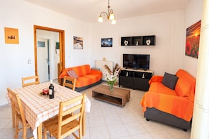 A living room with a dining area, a sofa set, a TV, and artwork on the walls. - Andronikos TownHouse- Priv Balcony Stay in Preveza (Preveza)