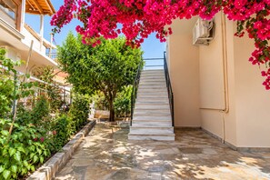 A stone staircase leading to a building entrance, surrounded by greenery and pink flowers. - Andronikos TownHouse- Priv Balcony Stay in Preveza (Preveza)