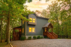 A two-story cabin with a porch and a staircase, surrounded by trees. - Bearway to Heaven 4BR, Slide, Hot Tub & Pool Table (Swanton)
