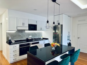 Une cuisine moderne avec des meubles blancs, un plan de travail noir et un îlot central doté de chaises.