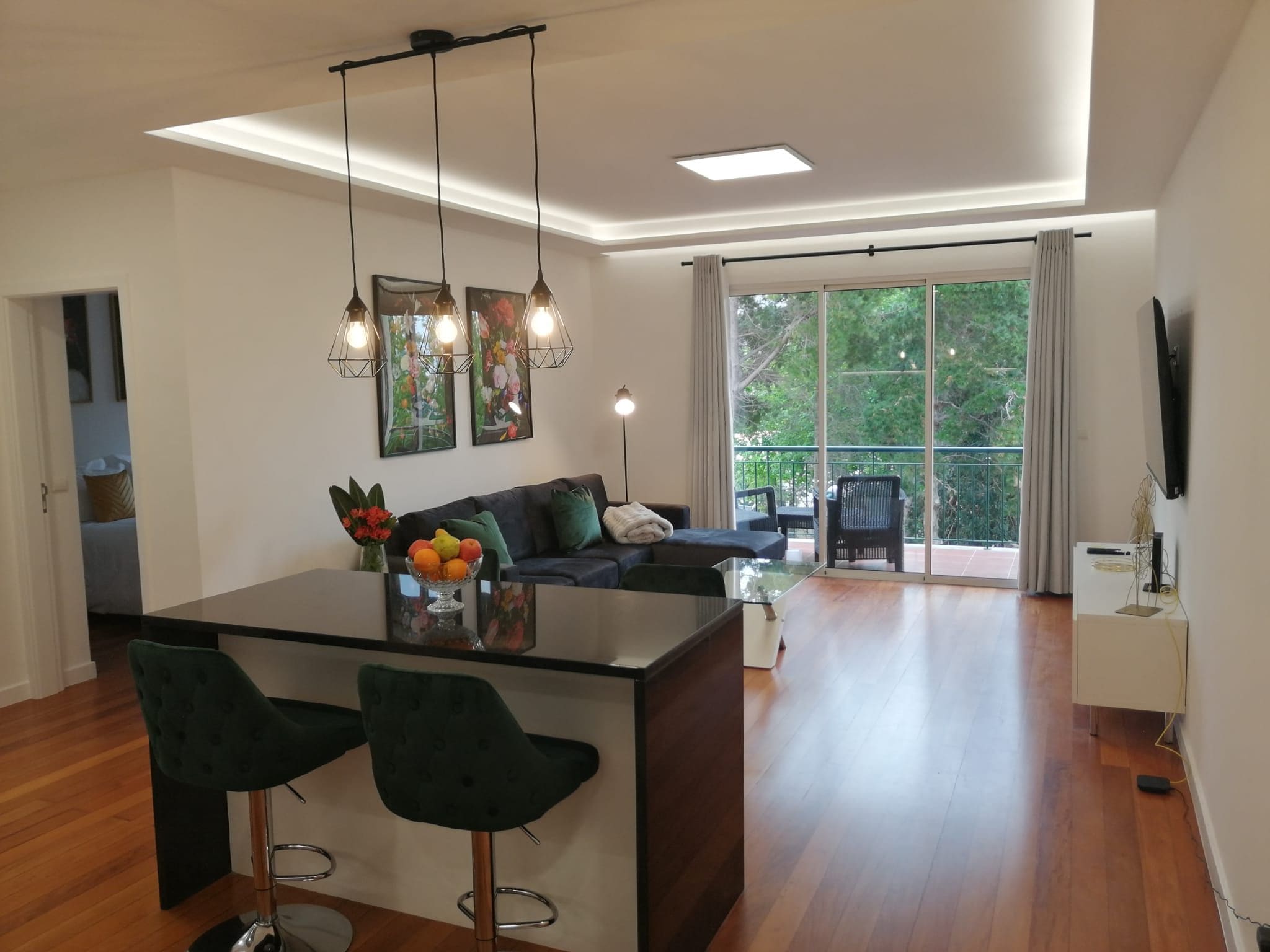 Een moderne woonruimte met een centraal eiland, barkrukken, een bank en een eettafel.