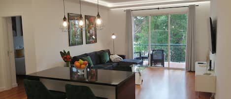 A modern living space with a central island, bar stools, a sofa, and a dining table.