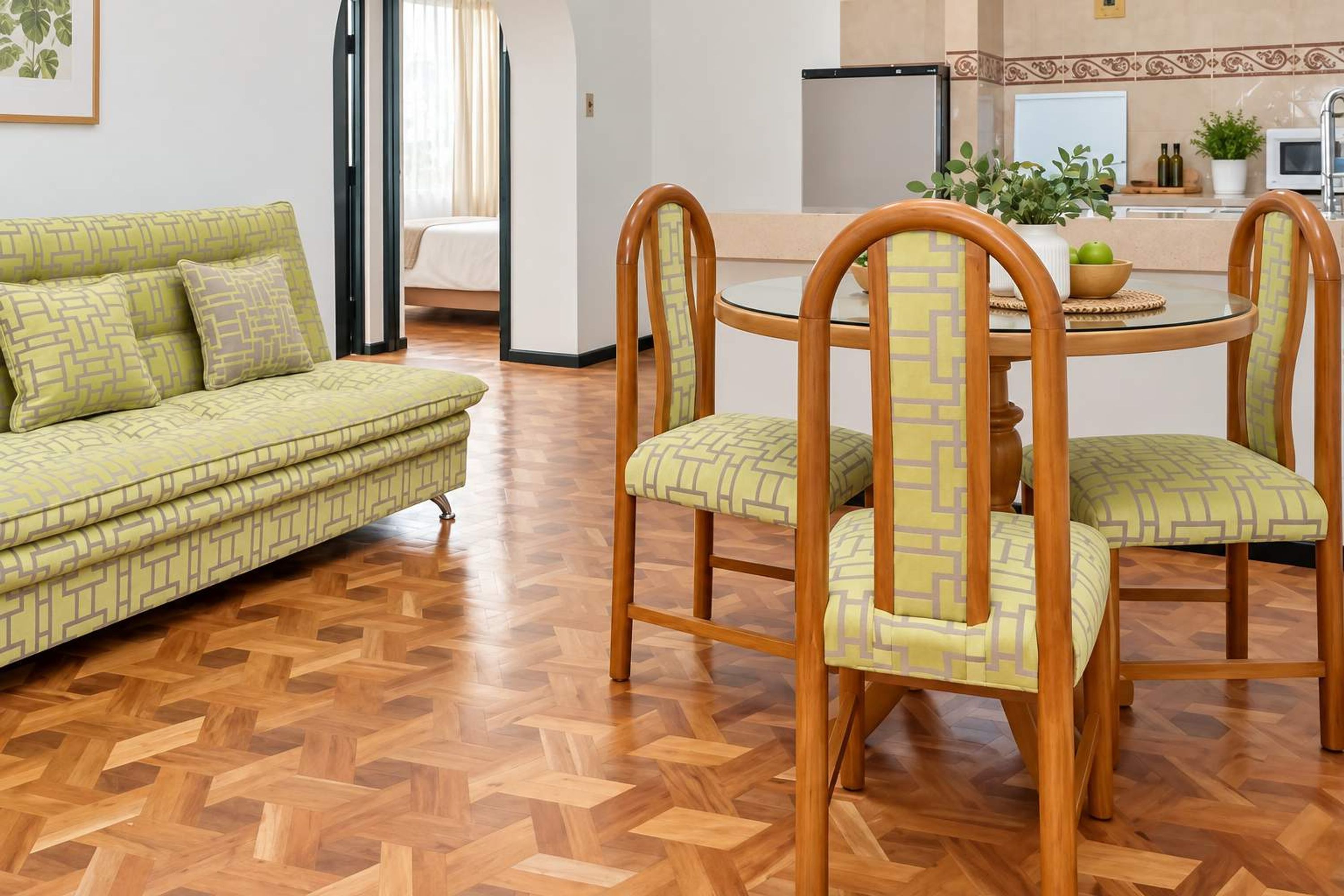 Una sala de estar con sofá, sillas, una mesa de comedor y una cocina al fondo.
