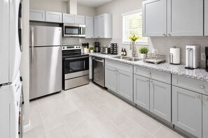 A modern kitchen with stainless steel appliances, grey cabinetry, and a tiled floor. - FIFA Stay 2BR Near NRG  DT   Med Center -1 (Houston)