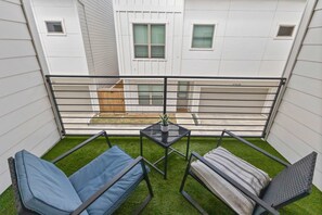 Ein Balkon mit einem kleinen Tisch, zwei Stühlen und einem Blumentopf.
