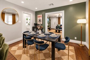 A dining area with a table set for four, chairs, a mirror, and a wall-mounted sign. - Honky Tonk Heights Home I 2 Kings I EV I Fire Pit (Houston)