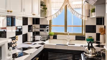 Une cuisine avec un dosseret à carreaux noirs et blancs, une cuisinière à gaz, un évier doté d’un robinet moderne et une fenêtre donnant sur le ciel.