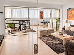 Una sala de estar moderna con sofá, reposapiés, mesa de centro y comedor con mesa y sillas.
