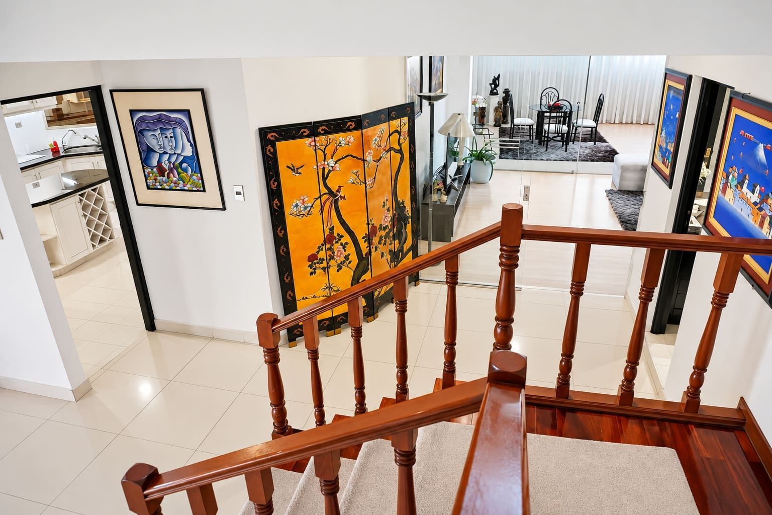 A staircase with wooden balusters leading to a living area with artwork on the walls.