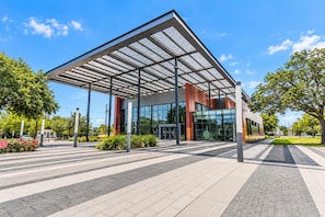 A modern building with a glass facade and a metal roof structure. - FIFA Stay 2BR Near NRG  DT   Med Center -3 (Houston)