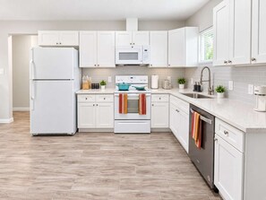 A modern kitchen with white cabinetry, a built-in microwave, a stove, and a dishwasher. - FIFA I 4BR Home I Backyard I Parking I Near NRG (Houston)