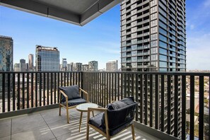 Un balcone con vista su un paesaggio urbano, caratterizzato da edifici moderni e un cielo sereno.