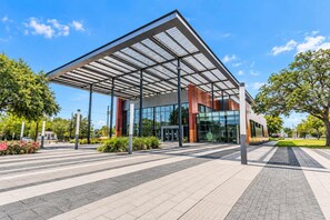 A modern building with a glass facade and a metal roof structure. - FIFA 2 Apt Bundle Near NRG  DT   Med Center - 12 (Houston)