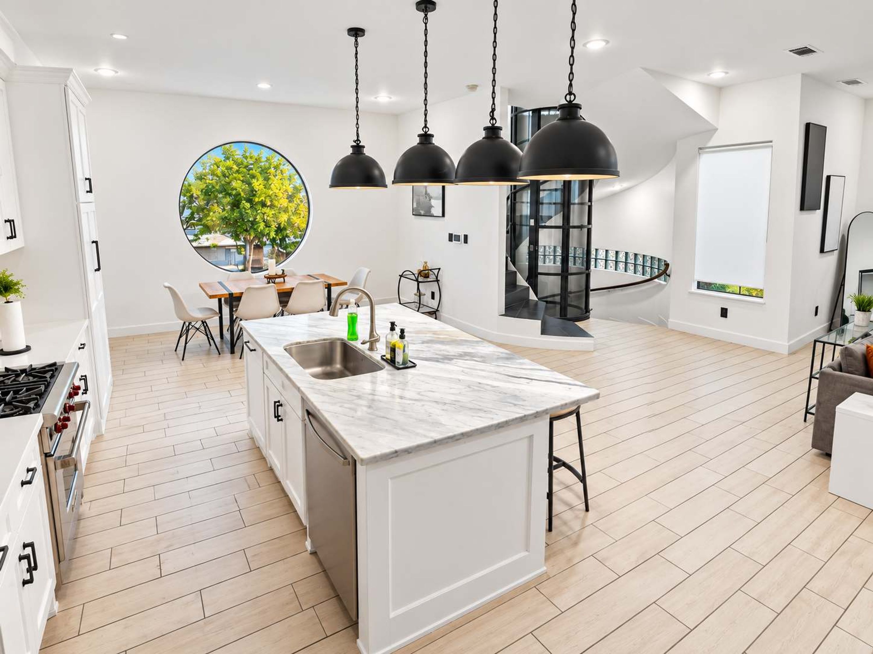 Een moderne keuken met een centraal eiland, hanglampen en uitzicht op de omgeving.