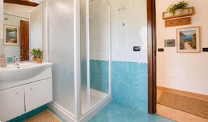 Ein Badezimmer mit Dusche, Waschbecken und Fliesen.
