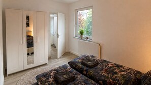 A bedroom with a bed, a wardrobe, a window with a view, and a radiator. - The Back Building at Karlsruhe Palace (Karlsruhe)