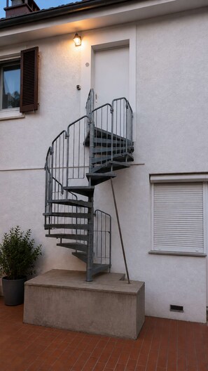 A spiral staircase leading to an upper floor, a potted plant, and a closed garage door. - The Back Building at Karlsruhe Palace (Karlsruhe)