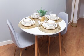 A round dining table set with white plates, gold-rimmed bowls, and gold cutlery. - Spacious Riverside 2-Bed Apartment | Sleeps 5 | Contractor Stays (Leeds)