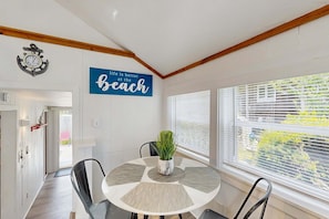 A dining area with a round table, chairs, a potted plant, and a wall with a motivational quote. - Cozy Cottage with Deck, Yard & Walk to the Beach (Dennis)
