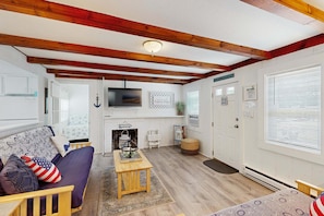 Ein gemütliches Wohnzimmer mit Kamin, Fernseher und einem Schild, auf dem 'BEACH happy place' steht.