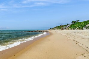A sandy beach with a rocky breakwater and a staircase leading up to a grassy area. - Adorable Cottage With Patio & Walk to Sea St Beach (Dennis)