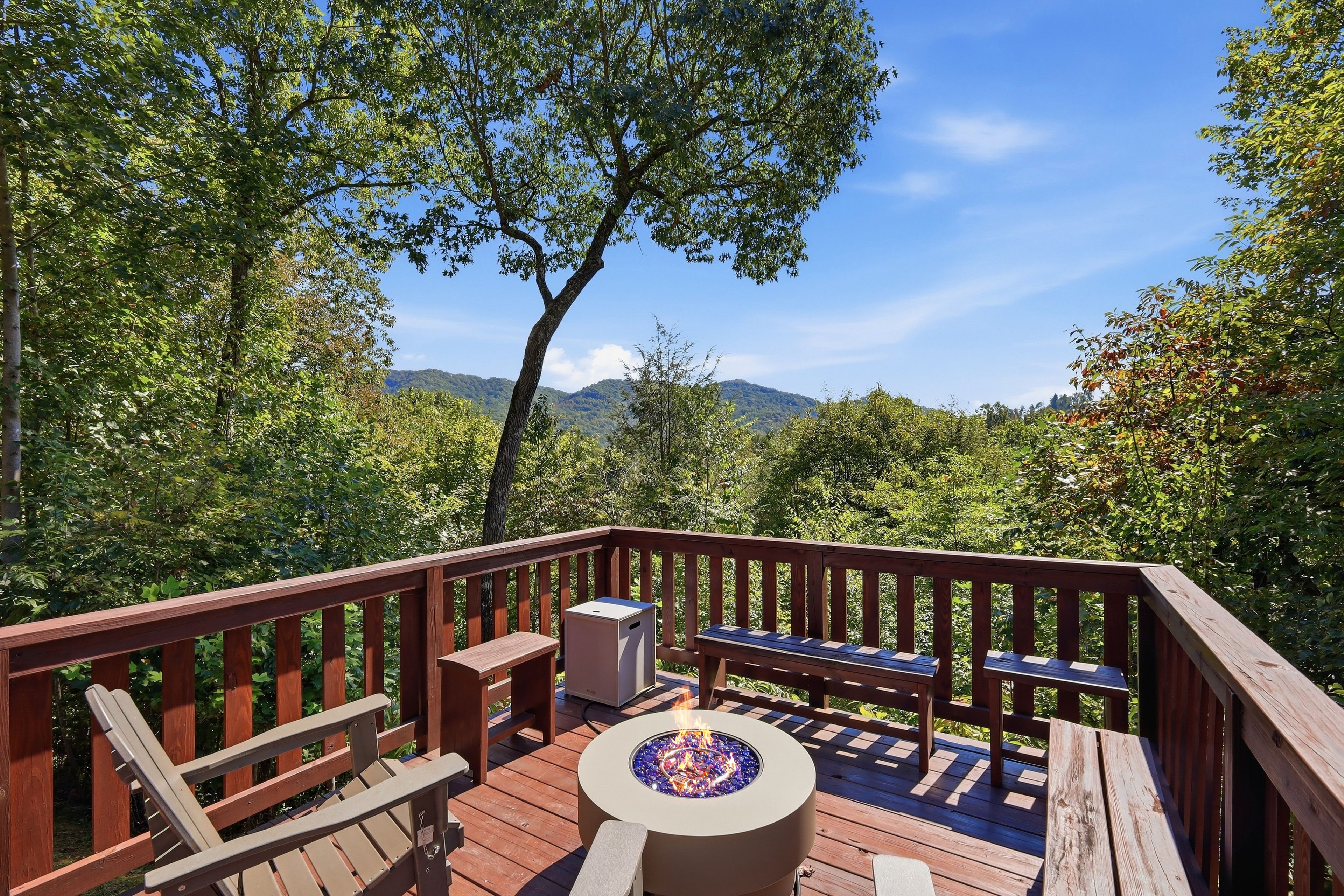 Une terrasse dotée d’un foyer extérieur, de sièges et offrant une vue sur une chaîne de montagnes boisées.
