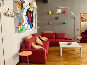 A modern living room with a red sectional sofa, a small round table, and a white coffee table. - BERGAMO ALTA SUITE - Spacious apartment in the heart of Bergamo Alta (Bergamo)