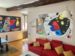 A living room with a red sofa, a coffee table, and abstract wall art. - BERGAMO ALTA SUITE - Spacious apartment in the heart of Bergamo Alta   (Bergamo)