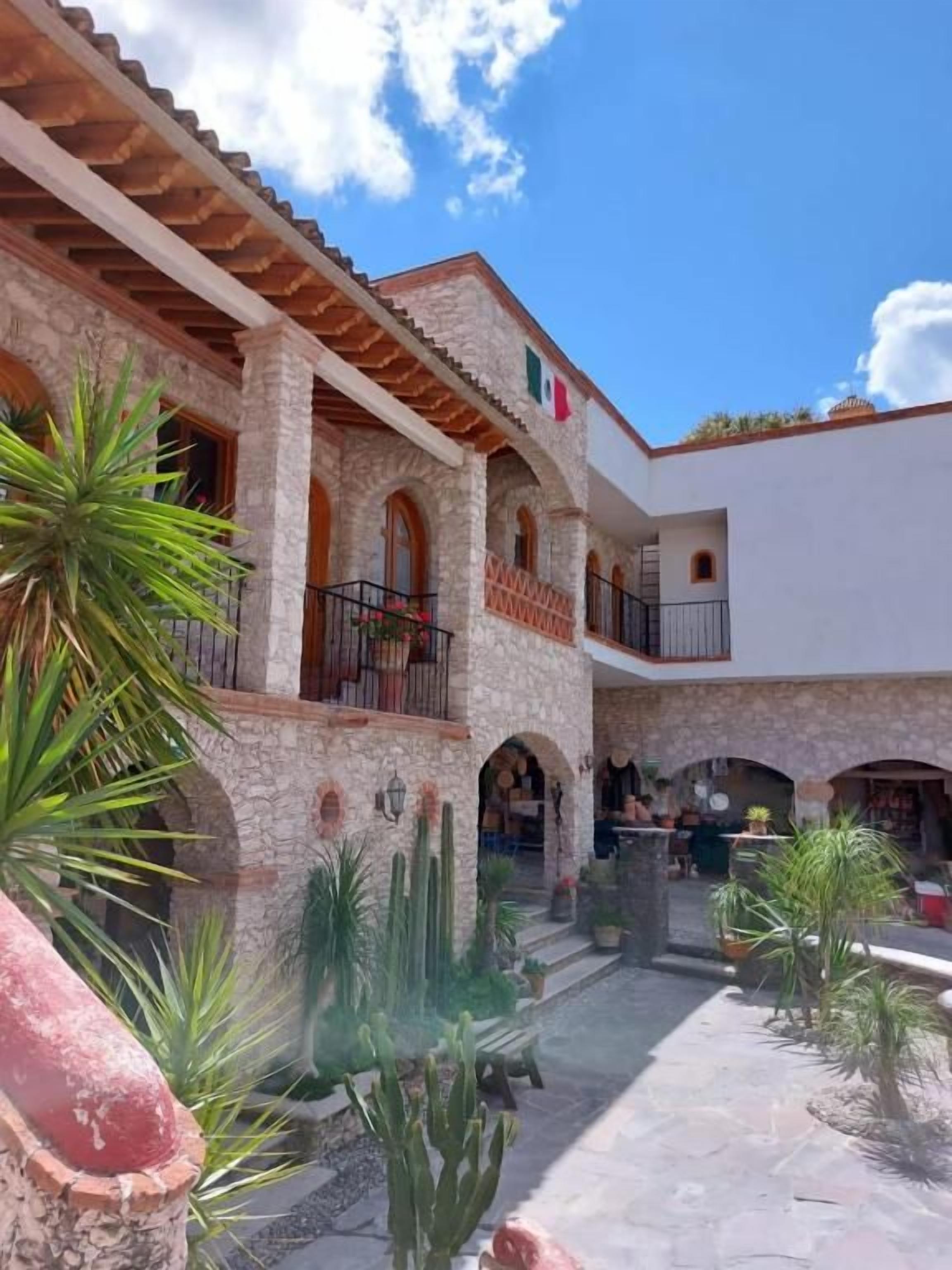 Un patio con un edificio de piedra, ventanas en arco y una piscina.