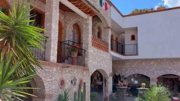 Un patio con un edificio de piedra, ventanas en arco y una piscina.