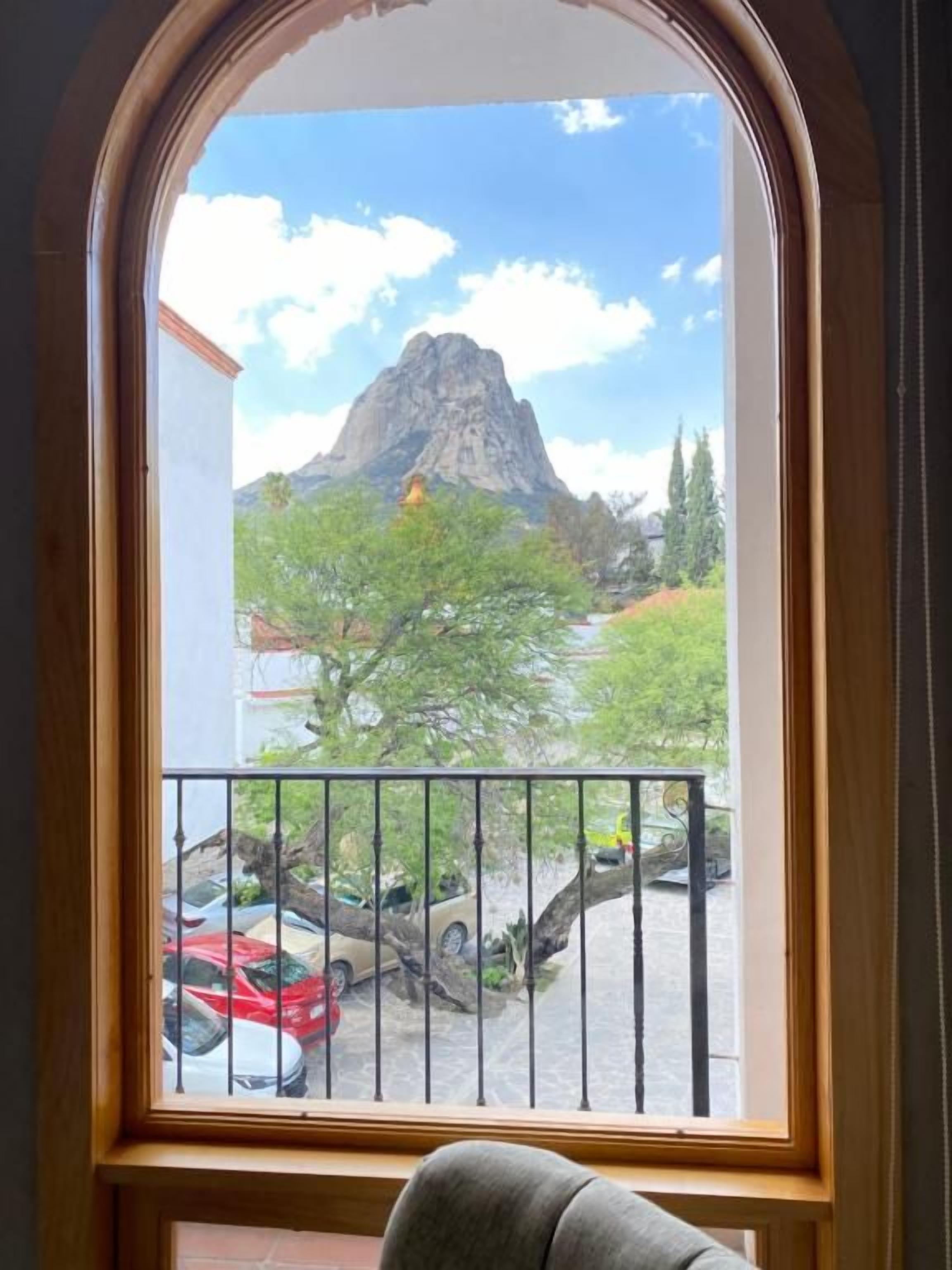Una ventana con vistas a una montaña y coches aparcados.