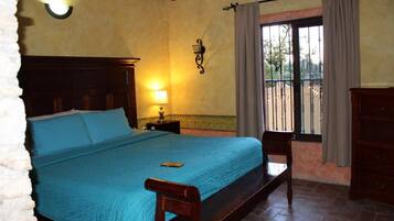 A bedroom with a bed, a nightstand, a lamp, a window with curtains, and a view of the outside.