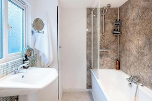 Ein Badezimmer mit einer Badewanne, einer Dusche und einem Waschbecken.