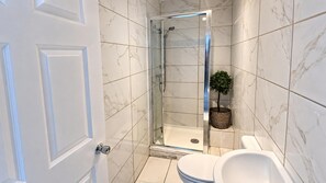 Ein Badezimmer mit einer Duschkabine, einer Toilette und einem Blumentopf.