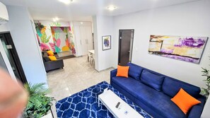 Ein modernes Wohnzimmer mit einem blauen Sofa, einem weißen Couchtisch und einem farbenfrohen abstrakten Gemälde.