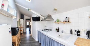 Una cocina moderna con azulejos blancos, estufa a gas, un lavamanos y encimeras de madera.