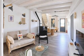 A spacious living area with a sofa, a coffee table, and a dining table with chairs. - Charming house in the heart of the salt marshes (Guérande)