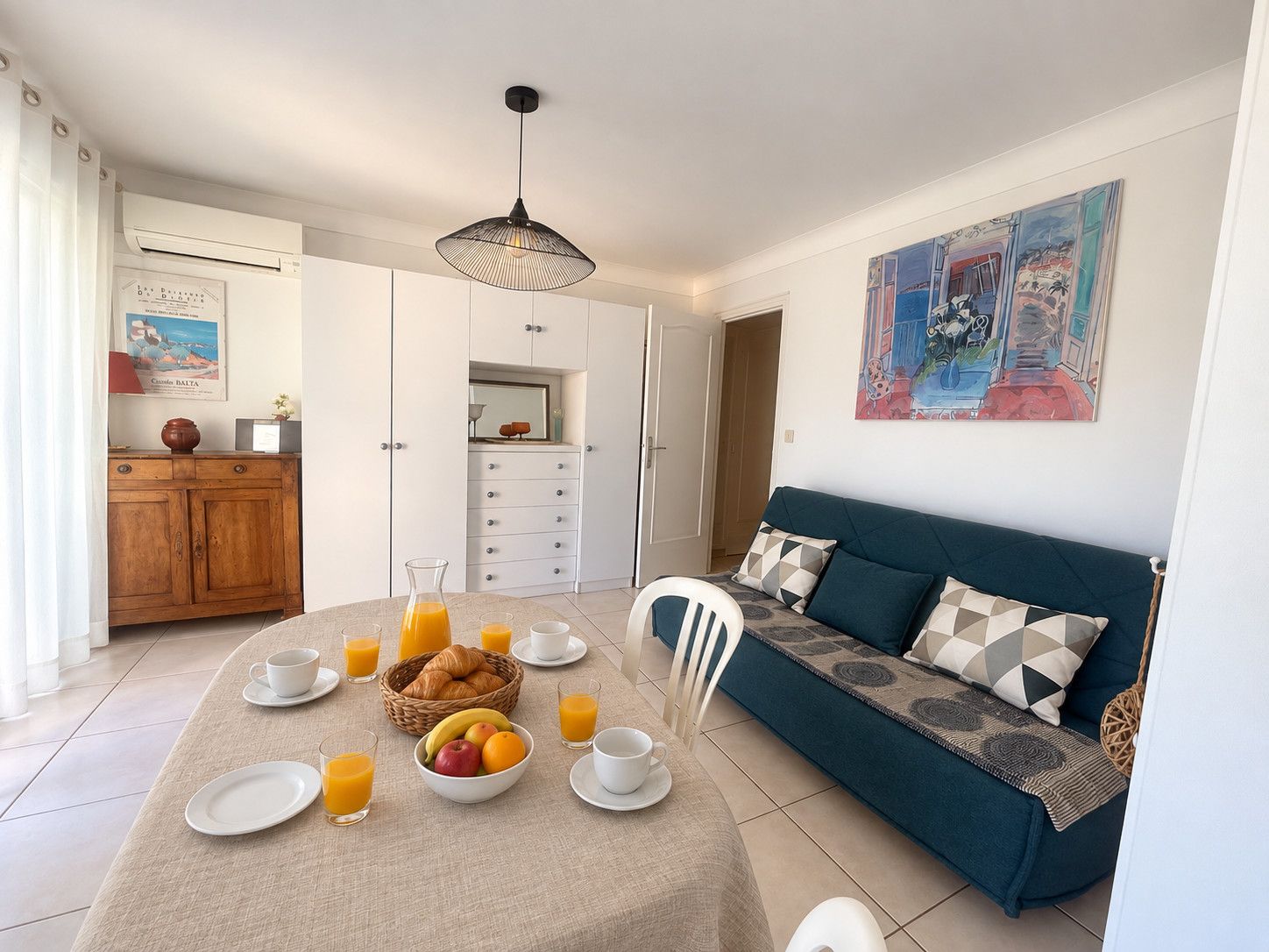 Een eetgedeelte met een ontbijttafel, een bank en een schilderij aan de muur.