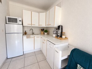 A kitchen with white appliances, including a microwave, refrigerator, and dishwasher, with wooden handles on the cabinets.