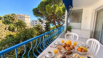 Un balcone con un tavolo apparecchiato per la colazione, con croissant, frutta e bevande.