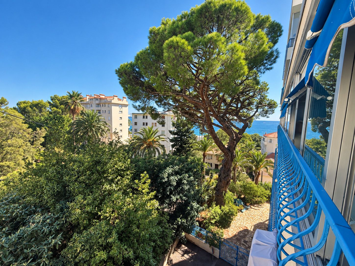 Ein Balkon mit Blick auf einen Baum, ein Gebäude und einen klaren Himmel.