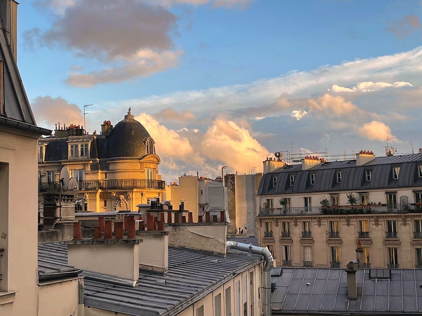 A cityscape with a prominent building featuring a dome and multiple chimneys.