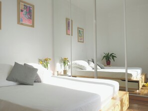 Habitación de hotel con dos camas, un espejo grande y una planta en maceta.