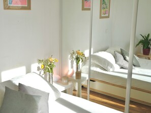 Un dormitorio con cama, mesitas de noche, un espejo y una planta en maceta.