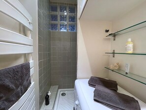 Ein Badezimmer mit Dusche, Toilette und Regalen mit Pflegeprodukten.