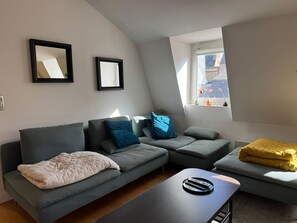 Un salon moderne avec un canapé d’angle, une table basse et une fenêtre donnant sur l’extérieur.