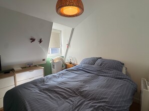 Une chambre à coucher avec un lit, une table de chevet et une fenêtre.