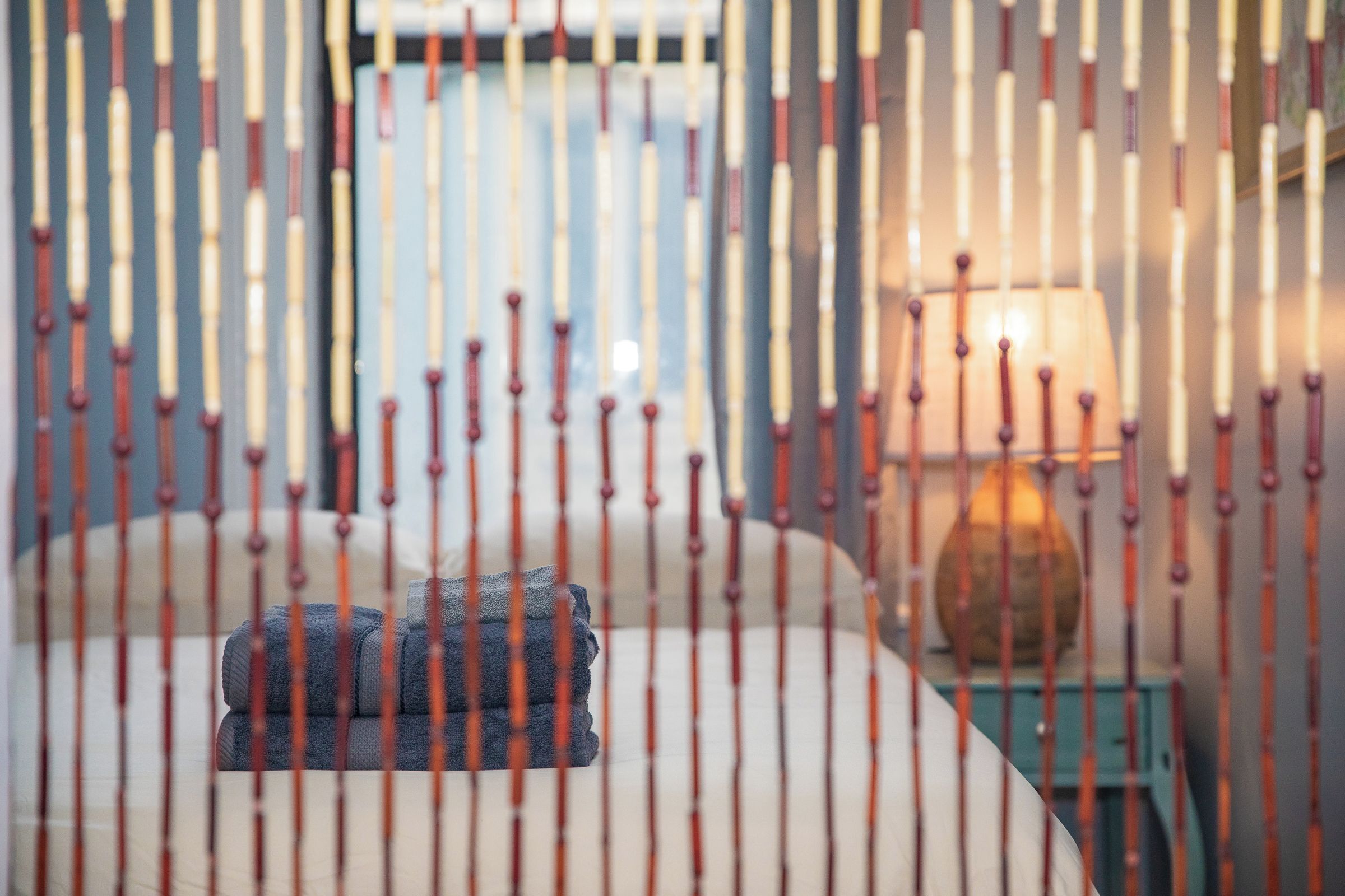 A bed with a folded blanket, a bedside lamp, and a nightstand with a decorative item.